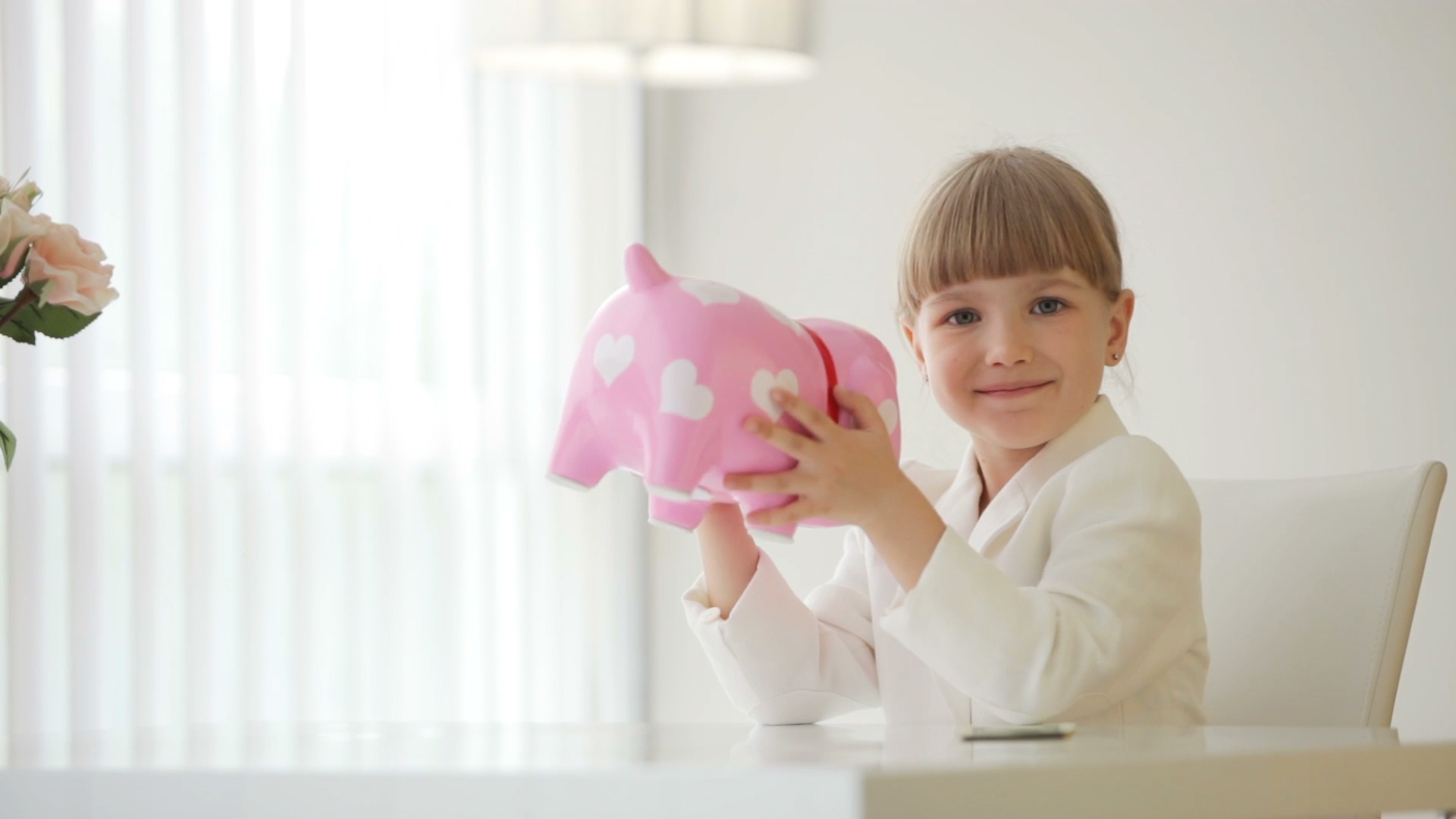 girl-sitting-at-table-and-holding-piggy-bank